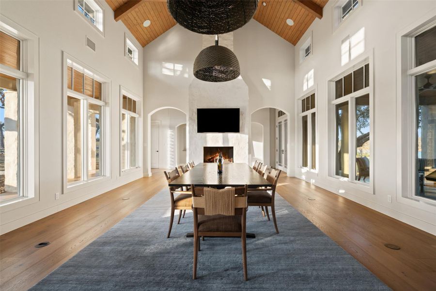 Dining area in Arcadia with a wooden ceiling with exposed beams, healthy amount of natural light, high vaulted ceiling, a fireplace, and wood finished floors
