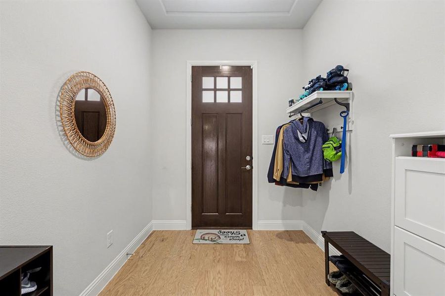 Entryway featuring a paneled door with window inserts, wood-finish flooring, and white baseboards