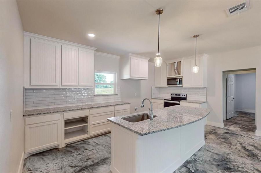 Kitchen with decorative backsplash, stainless steel appliances, sink, a center island with sink, and white cabinetry