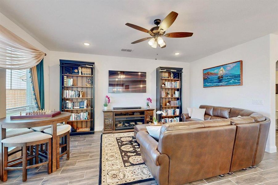 Living area featuring wood tiled floors, a ceiling fan, and recessed lighting