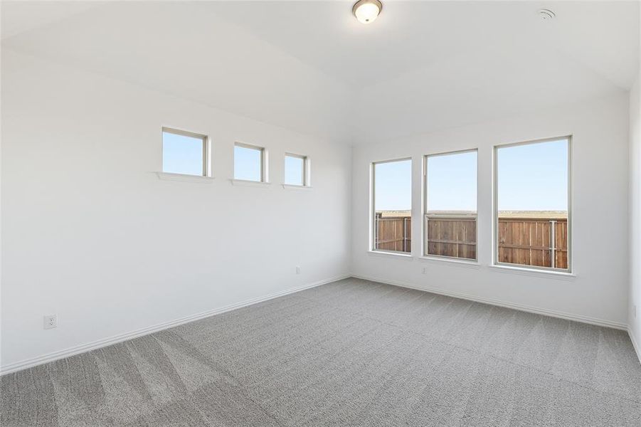 Spacious room featuring vaulted ceilings, a contemporary flush-mount light fixture, and plush gray carpeting