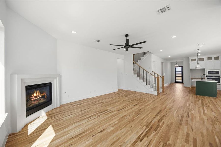Unfurnished living room with a glass covered fireplace, light wood finished floors, ceiling fan, and recessed lighting