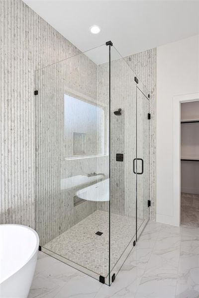 Bathroom with a stall shower, a freestanding tub, light marble finish flooring, and a walk in closet
