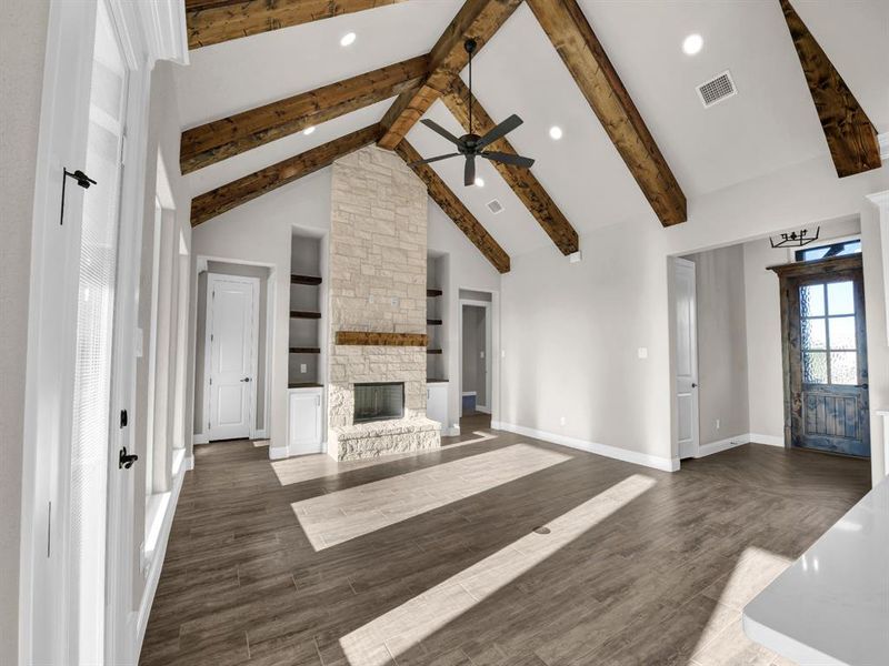 Living room featuring beam ceiling, a fireplace, dark hardwood / wood-style flooring, and high vaulted ceiling