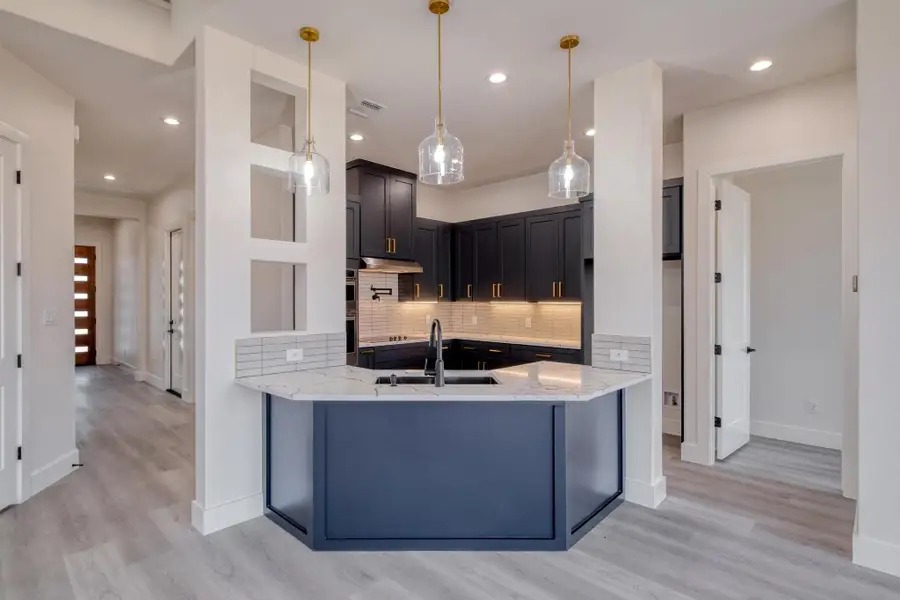 Kitchen featuring visible vents, a sink, tasteful backsplash, a peninsula, and light stone countertops