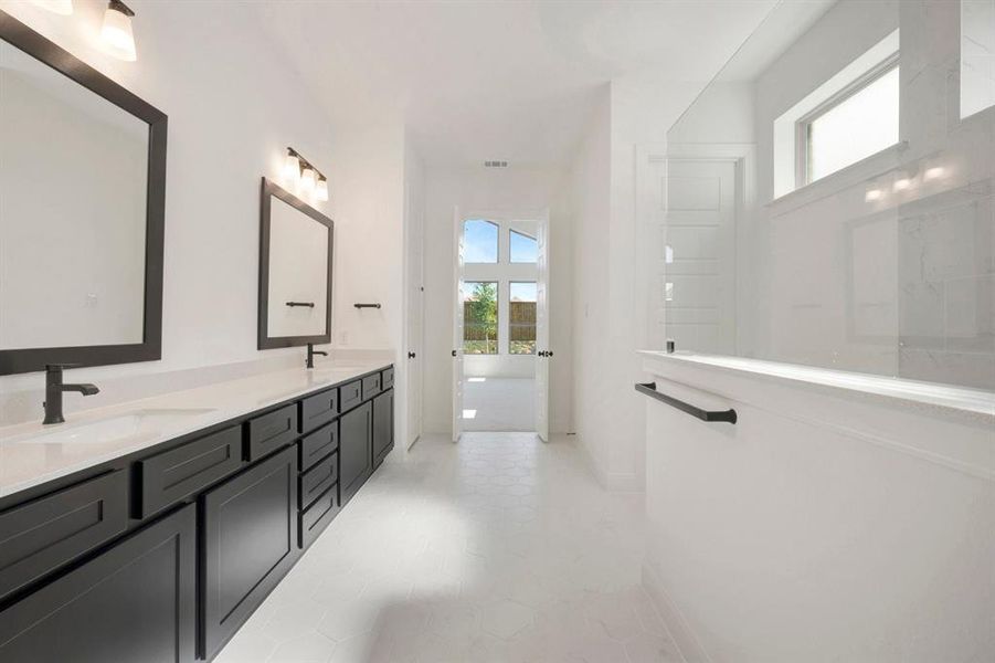 Spacious bathroom featuring a dual vanity with dark cabinetry and light-toned countertops, contemporary square mirrors, and matte black hardware Spacious bathroom featuring a dual vanity with dark cabinetry and light-toned countertops, contemporary square mirrors, and matte black hardware
