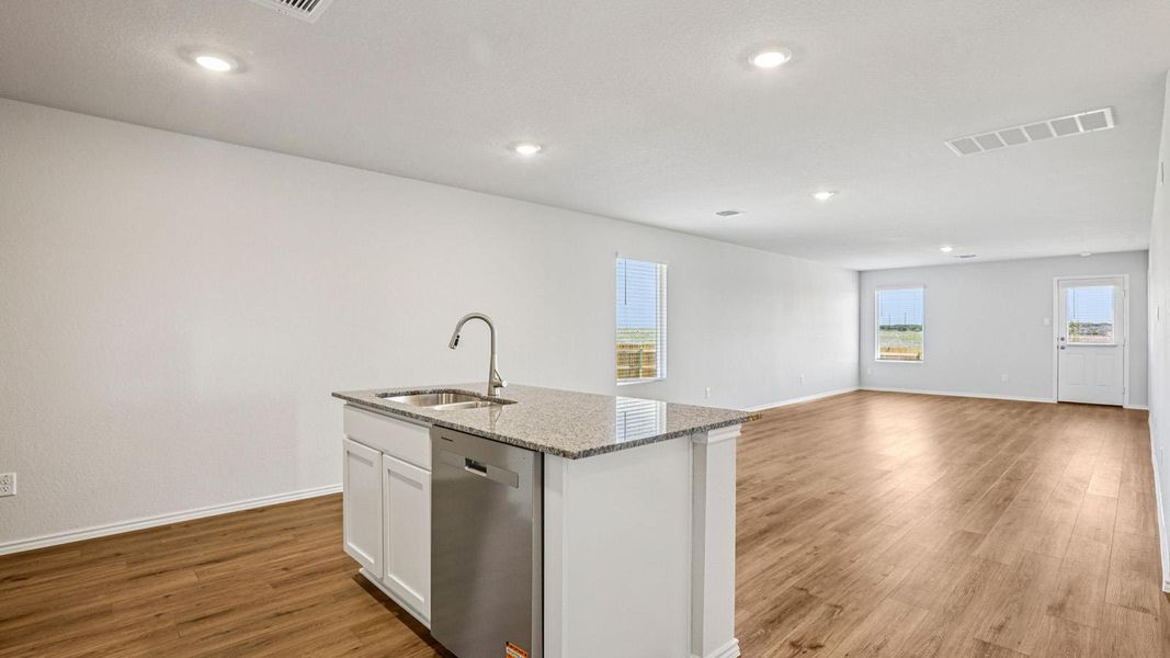 Open-concept living area featuring wood-finish flooring, recessed lighting, and ample natural light through multiple windows Open-concept living area featuring wood-finish flooring, recessed lighting, and ample natural light through multiple windows