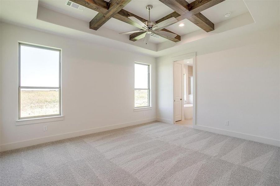 Spare room with beam ceiling, coffered ceiling, ceiling fan, and light colored carpet