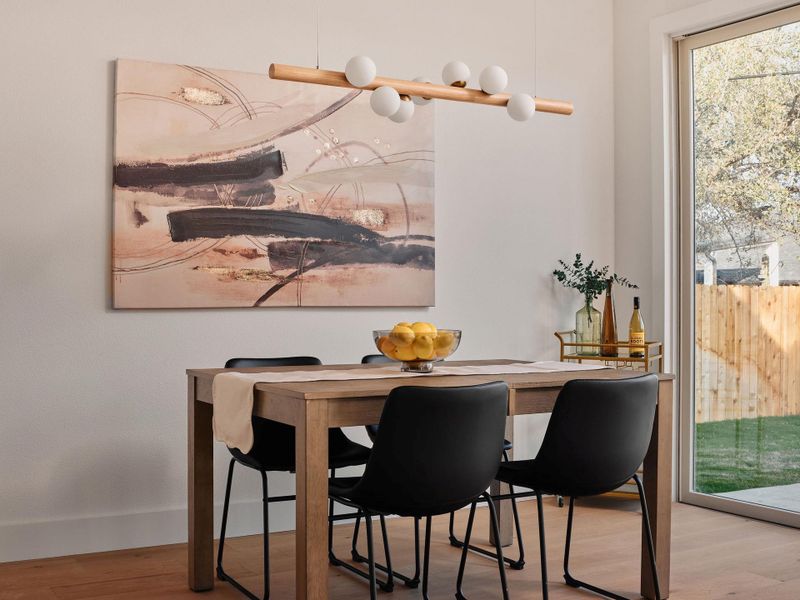 Open-concept dining area featuring wood-finish flooring, a contemporary linear chandelier, and a sliding glass door to the exterior