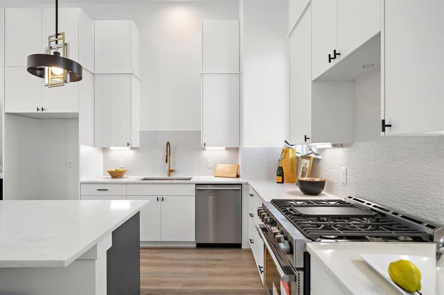 The kitchen in this beautiful Jamye plan has tall upper cabinets, quartz countertops, stunning, faux stacked stone backsplash and gorgeous hardware.