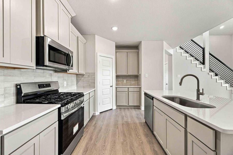 Kitchen with gray shaker cabinets, white quartz countertops, and stainless steel appliances Kitchen with gray shaker cabinets, white quartz countertops, and stainless steel appliances