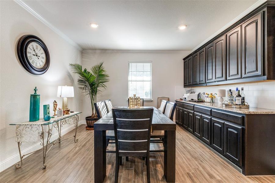 Dining area with ornamental molding and light hardwood / wood-style floors