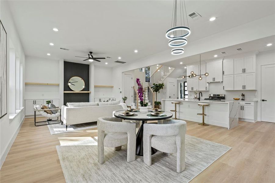 Dining area featuring stairs, light wood-style flooring, recessed lighting, a ceiling fan, and a chandelier
