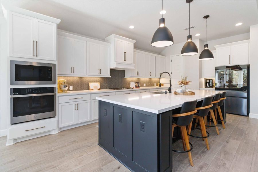 Kitchen featuring backsplash, appliances with stainless steel finishes, white cabinets, a breakfast bar area, and recessed lighting Kitchen featuring backsplash, appliances with stainless steel finishes, white cabinets, a breakfast bar area, and recessed lighting