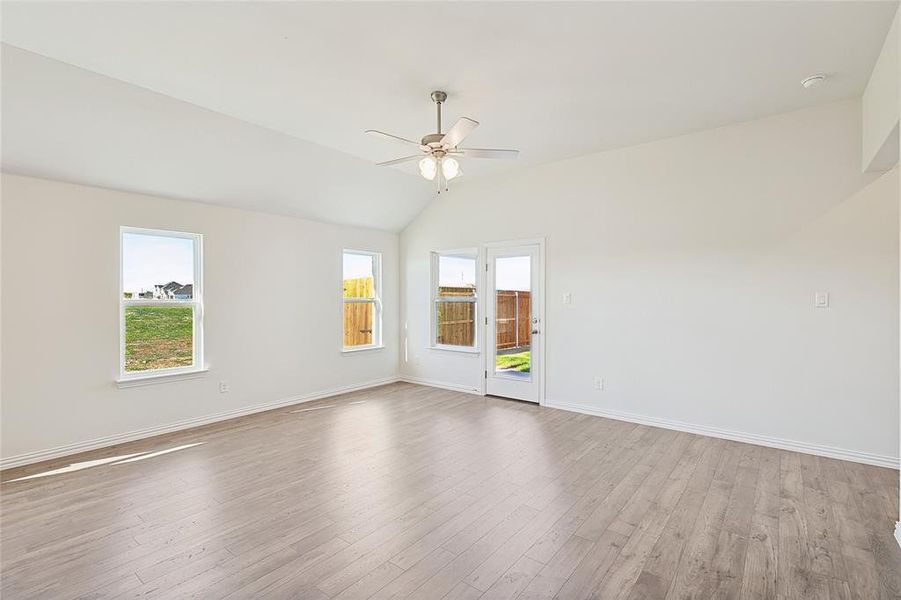 Spare room featuring ceiling fan, vaulted ceiling, and light wood-type flooring