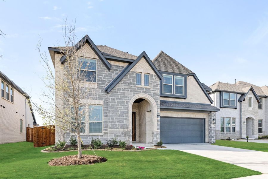 Two-story stone and brick home with arched entry, two-car garage, and manicured front lawn Two-story stone and brick home with arched entry, two-car garage, and manicured front lawn