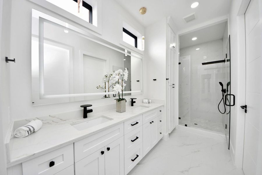 The primary bedroom/guest suite features a spa-like bathroom with dual sinks, a spacious-shower, and a large walk-in closet, combining luxury and functionality in one elegant retreat.