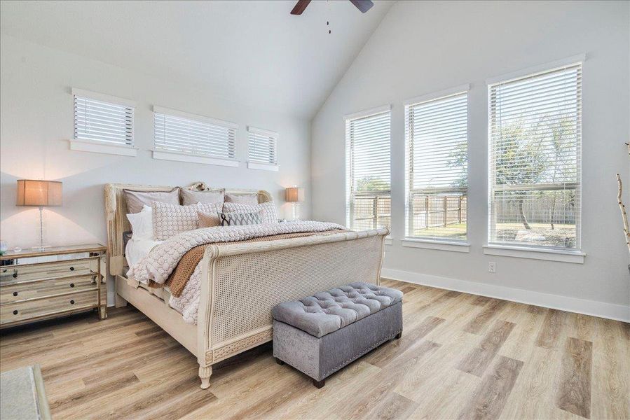 Bedroom with light wood-style flooring, vaulted ceiling, multiple windows, and ceiling fan Bedroom with light wood-style flooring, vaulted ceiling, multiple windows, and ceiling fan
