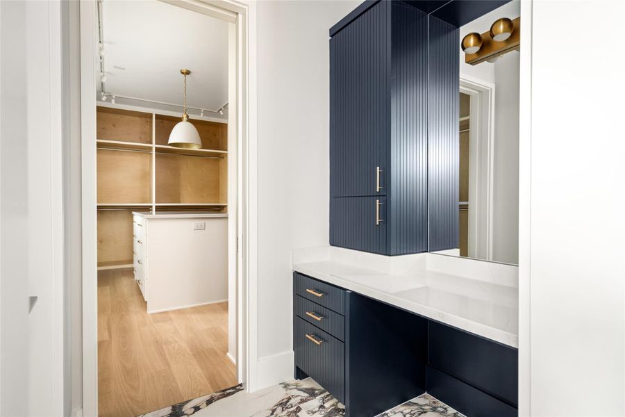 A built-in vanity offers a seamless transition into the expansive primary closet beyond.