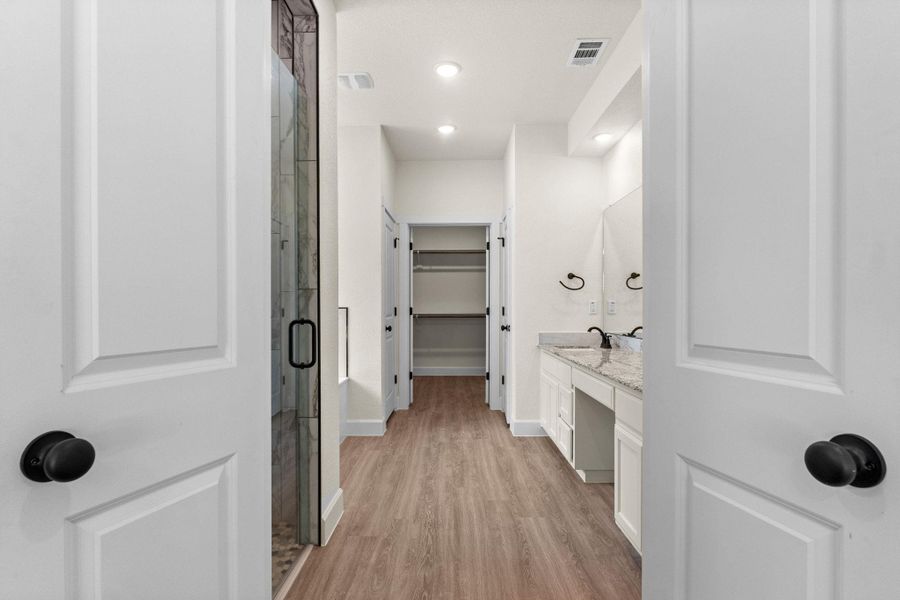 Bathroom with vanity, a spacious closet, light wood-style flooring, recessed lighting, and a shower stall