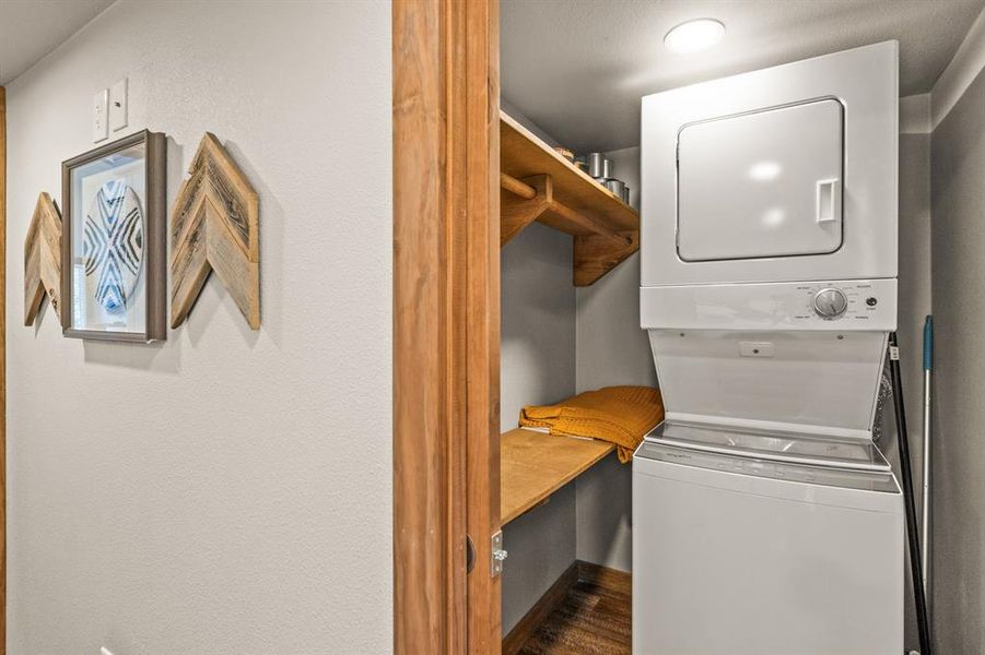 Washroom featuring stacked washer and clothes dryer and dark wood-style floors