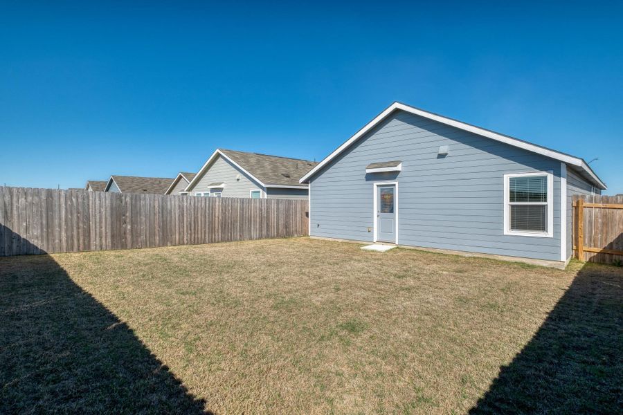 The property features a fenced yard with a patch of lawn, providing a private outdoor space