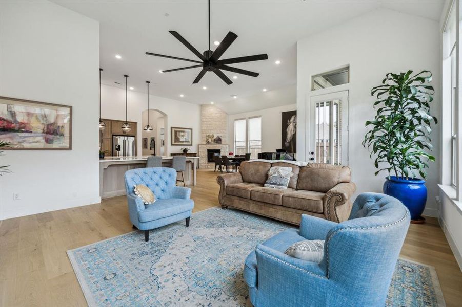 Living room featuring a ceiling fan, vaulted ceiling, light wood finished floors, and recessed lighting