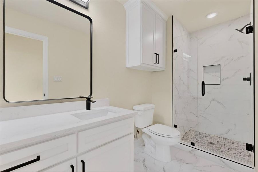 Bathroom featuring a white vanity with an integrated sink, black faucet, and a large framed mirror