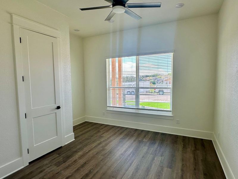 Unfurnished room featuring a ceiling fan, dark wood finished floors, and a textured wall