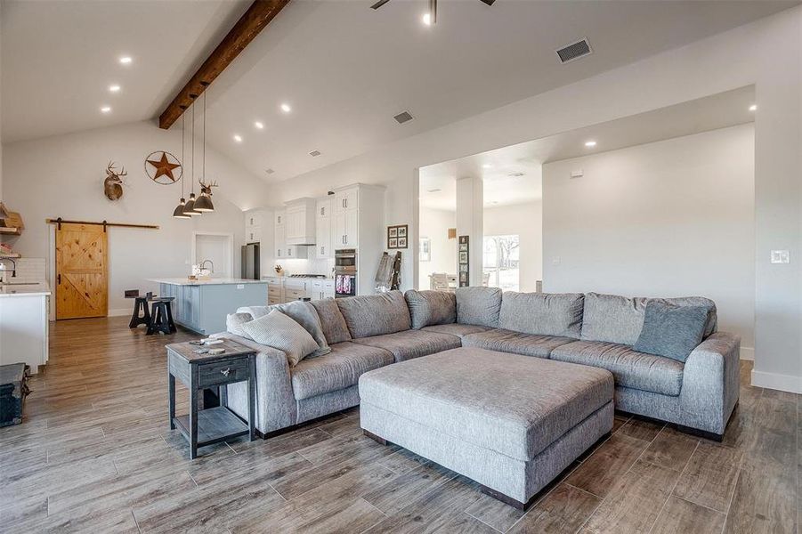 Living room featuring beamed ceiling, high vaulted ceiling, a barn door, and sink