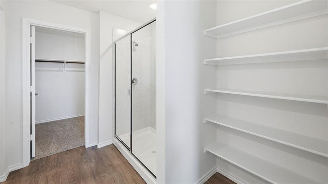Full bath featuring a spacious closet, a shower stall, and dark wood-style floors Full bath featuring a spacious closet, a shower stall, and dark wood-style floors