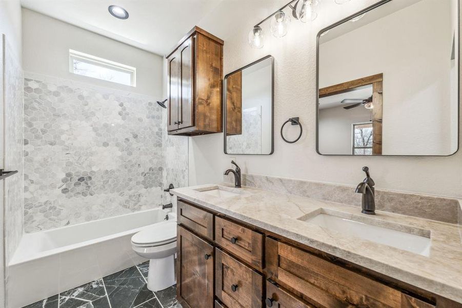 Full bathroom with toilet, a sink, double vanity, and bathing tub / shower combination