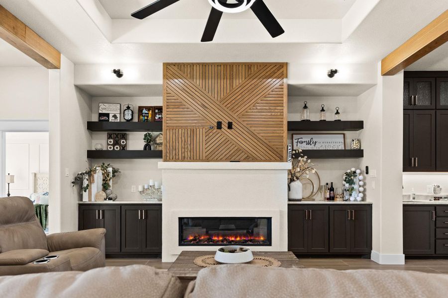 Living area with wet bar, a ceiling fan, and a glass covered fireplace Living area with wet bar, a ceiling fan, and a glass covered fireplace