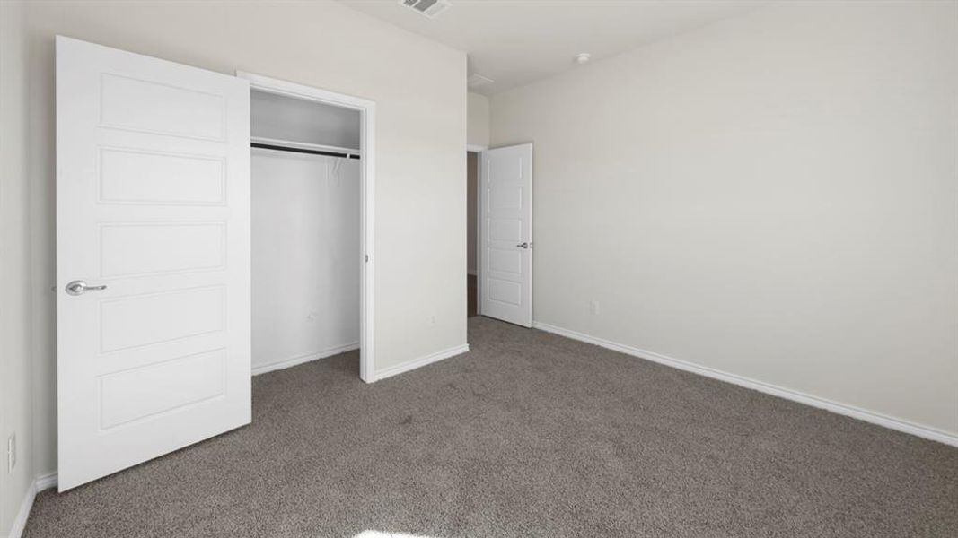 Bedroom featuring plush gray carpeting, light neutral wall tones, white baseboards, and a white interior door with contemporary paneling and chrome hardware Bedroom featuring plush gray carpeting, light neutral wall tones, white baseboards, and a white interior door with contemporary paneling and chrome hardware