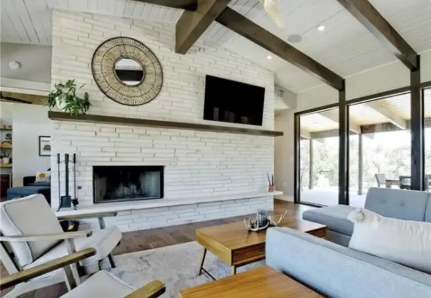 Living area featuring beamed ceiling, wood finished floors, a fireplace, and high vaulted ceiling Living area featuring beamed ceiling, wood finished floors, a fireplace, and high vaulted ceiling