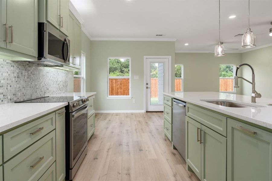 Kitchen featuring decorative backsplash, light wood-type flooring, stainless steel appliances, and a wealth of natural light