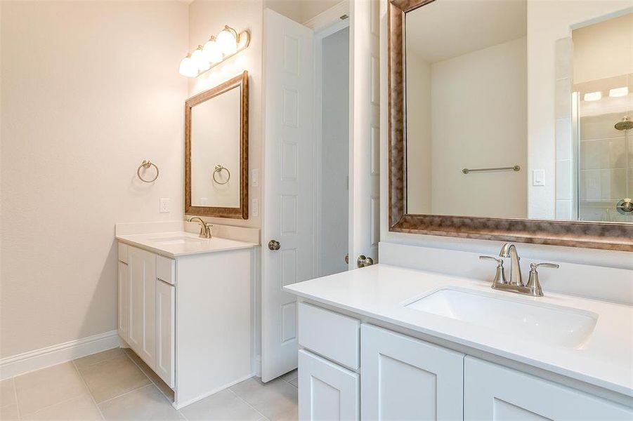 Bathroom with dual bowl vanity and tile patterned floors