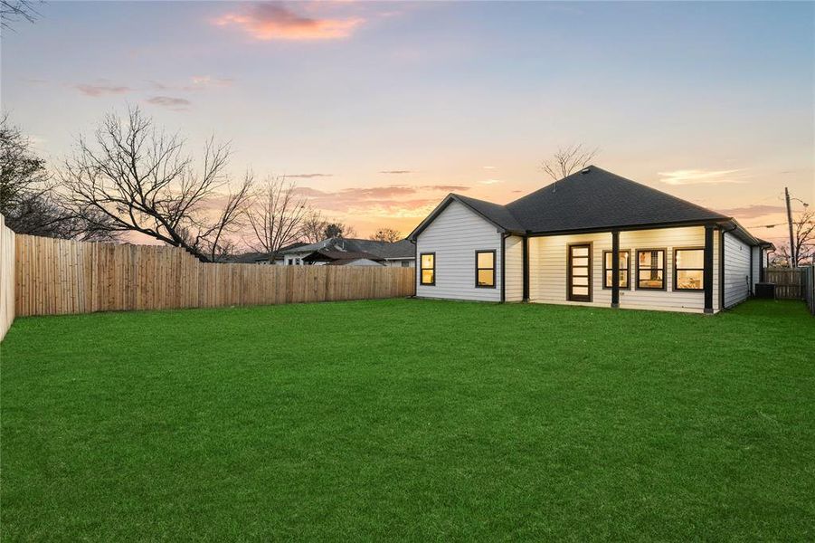 Back house at dusk with a yard