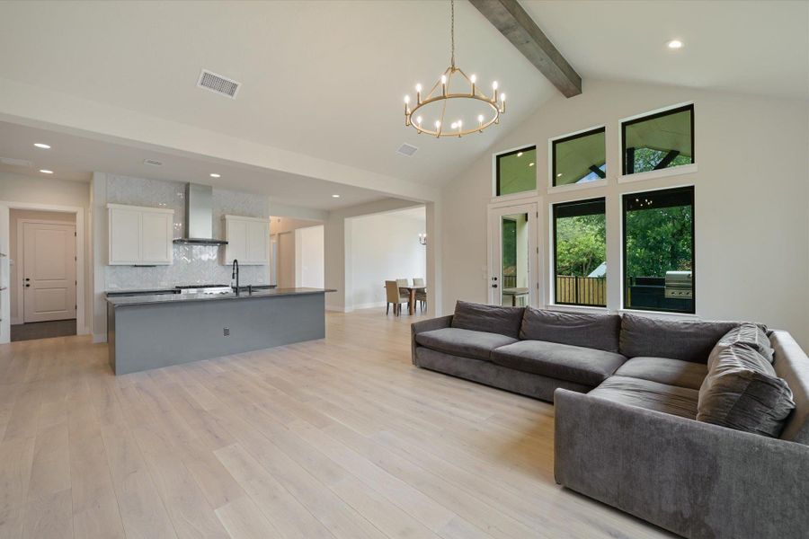 An open-concept living area with vaulted ceilings and abundant natural light from large windows.