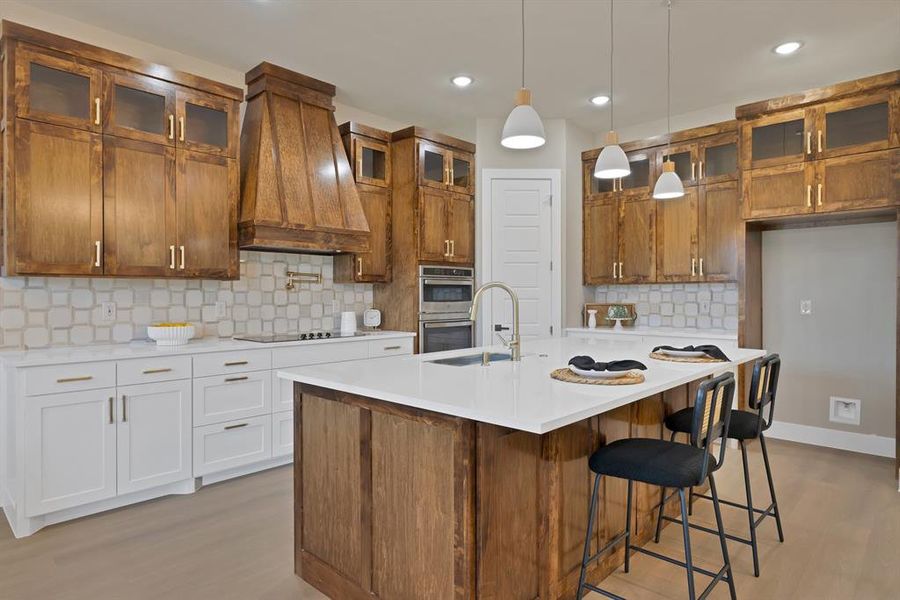 Kitchen featuring stainless steel double oven, custom exhaust hood, a sink, light wood finished floors, and recessed lighting