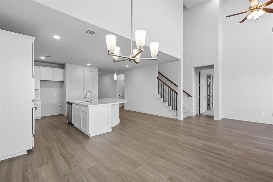 Kitchen featuring a kitchen island with sink, a chandelier, hanging light fixtures, white cabinets, and light wood-style flooring Kitchen featuring a kitchen island with sink, a chandelier, hanging light fixtures, white cabinets, and light wood-style flooring