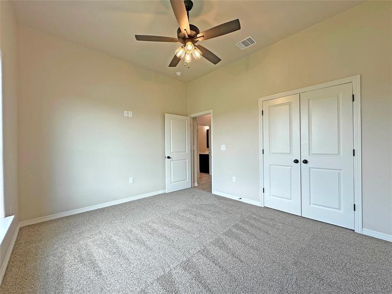 Unfurnished bedroom featuring carpet flooring, a ceiling fan, and a closet