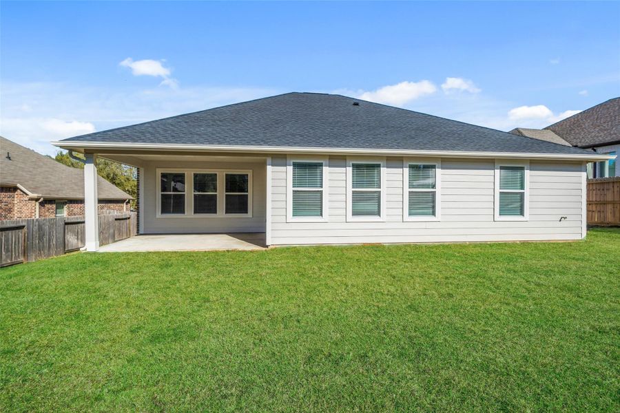 Notice the whole house gutters! Shown here is a view of the large covered back patio from the center of the yard.