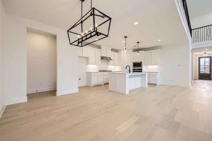 Kitchen featuring decorative backsplash, white cabinetry, light wood finished floors, a chandelier, and recessed lighting Kitchen featuring decorative backsplash, white cabinetry, light wood finished floors, a chandelier, and recessed lighting