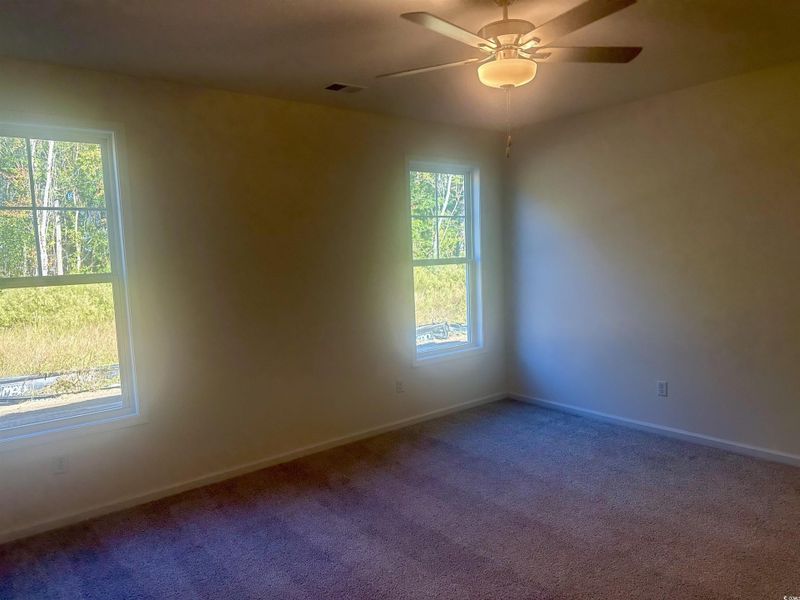 Carpeted empty room with baseboards and a ceiling fan