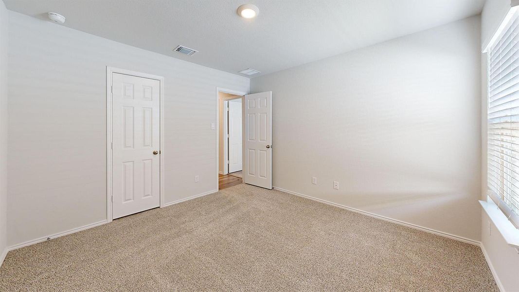 Unfurnished bedroom featuring light carpet and baseboards