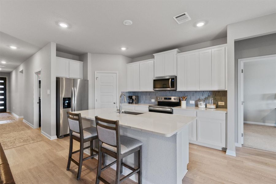 Kitchen with a central island featuring a white countertop and seating for two Kitchen with a central island featuring a white countertop and seating for two
