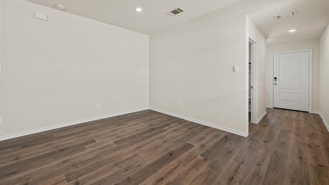 Expansive room featuring wood-finish flooring, white baseboards, recessed lighting, and a neutral wall color