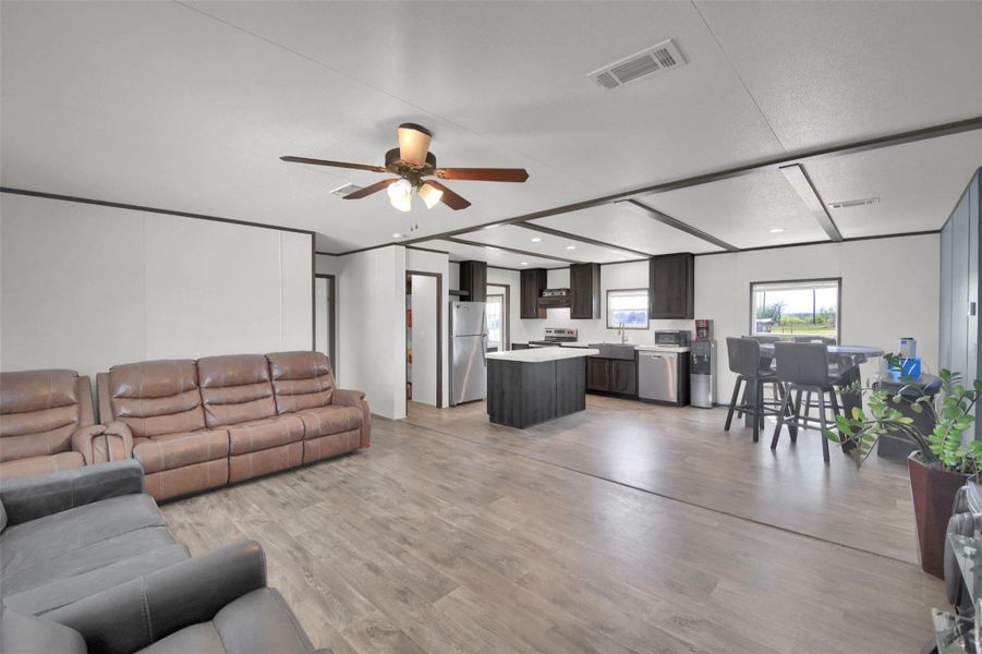 Living area with light wood-type flooring, ceiling fan, and beamed ceiling