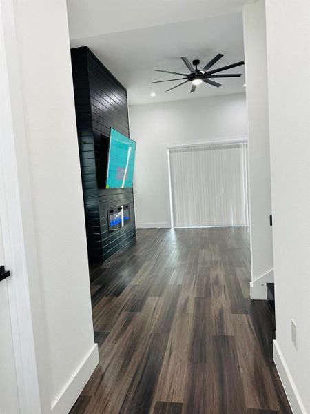 Unfurnished living room with ceiling fan, dark wood finished floors, a fireplace, and recessed lighting Unfurnished living room with ceiling fan, dark wood finished floors, a fireplace, and recessed lighting